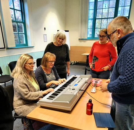 2 women sat at keyboard with two women and a man observing